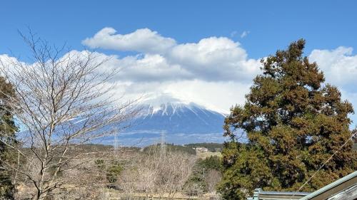 a snow covered mountain in the distance with trees and a bench at Torinami Fuji View House in Fujinomiya