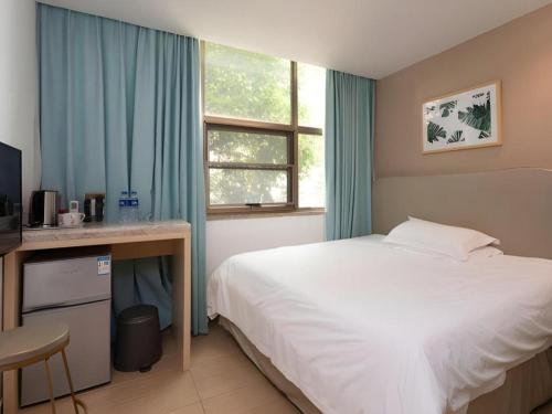 a bedroom with a bed and a desk and a window at Leisurely Hotel Shenzhen in Shenzhen