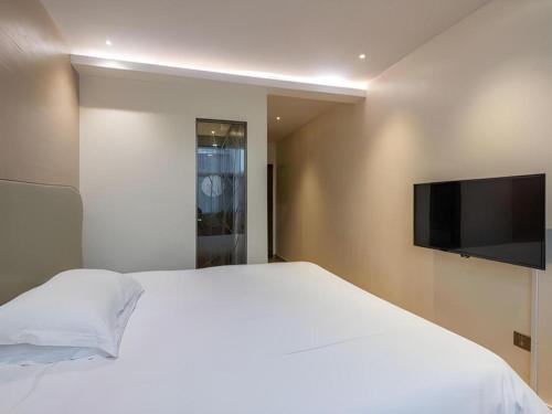 a bedroom with a white bed and a flat screen tv at Leisurely Hotel Shenzhen in Shenzhen