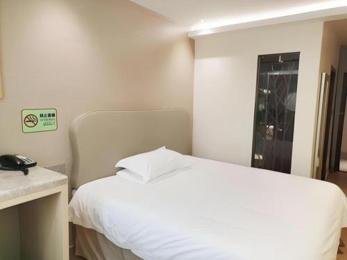 a bedroom with a white bed and a telephone at Leisurely Hotel Shenzhen in Shenzhen