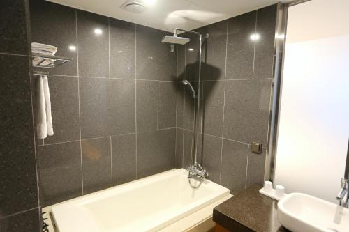 a bathroom with a bath tub and a sink at Asia Jeju in Jeju