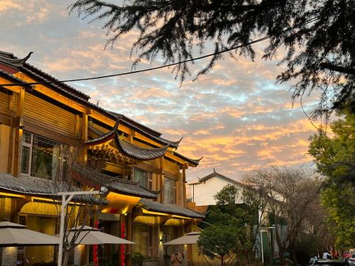 a building with a sunset in the background at Designer Bed and Breakfast Under the Green Trees in Lijiang