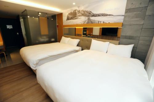 two twin beds in a hotel room with at Asia Jeju in Jeju