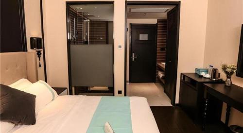 a bedroom with a bed and a desk and a door at Xana Hotelle·Ji'nan Hi-tech Zone Century Avenue Tangye in Jinan