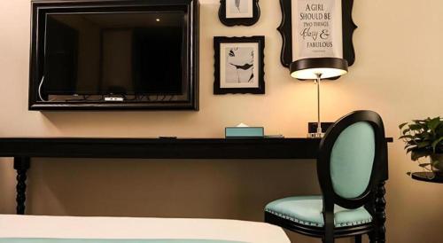 a room with a desk with a tv and a chair at Xana Hotelle·Ji'nan Hi-tech Zone Century Avenue Tangye in Jinan