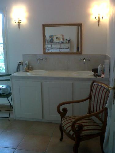 La salle de bains est pourvue de 2 lavabos, d'une chaise et d'un miroir. dans l'établissement BASTIDE DE CHARME PISCINE PRIVATIVE GORGES HERAULT, à Le Causse-de-la-Selle