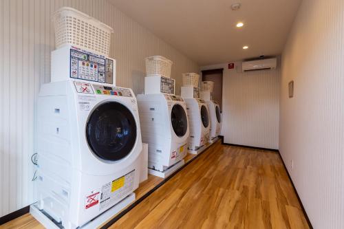 a row of washing machines are lined up in a laundry room at HOTEL R9 The Yard Mizunami in Mizunami