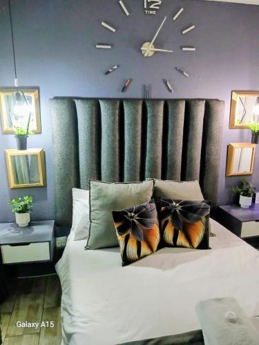 a bedroom with a large bed with a clock on the wall at Mitchell's Guesthouse in Parow