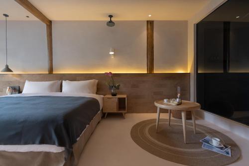a bedroom with a large bed and a table at Designer Bed and Breakfast Under the Green Trees in Lijiang