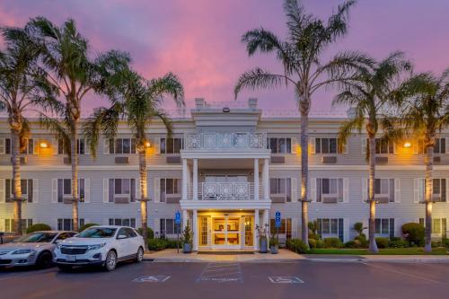 a large white building with palm trees in a parking lot at Best Western Luxury Inn in Tracy