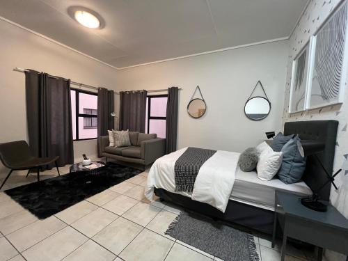 a bedroom with a bed and a couch and a chair at The Lagoon in Pretoria