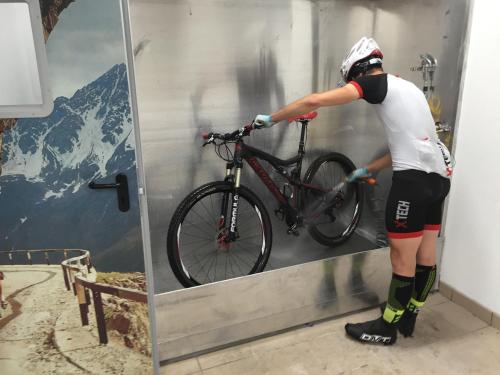 a man is putting a bike in a mirror at Hotel Garni Pegrà in Ponte di Legno