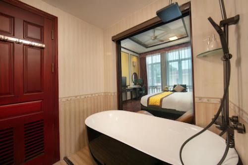 a bathroom with a bath tub and a bedroom at Royal Hotel & Spa Bắc Ninh in Ðồng Ky