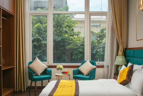 a hotel room with a bed and two chairs and a window at Royal Hotel & Spa Bắc Ninh in Ðồng Ky