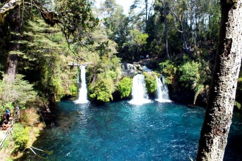 a group of waterfalls in a river in a forest at Cabañas Los Canelos Hermosa granja en Pucón in Pucón