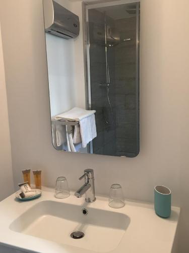 een wastafel in de badkamer met een spiegel en een douche bij B&B Lily et Paul in Bédoin
