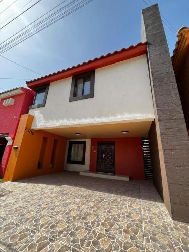 a red and white house with a driveway at Casa cerca de cosulado in Senecú