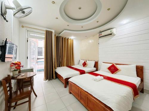 a hotel room with two beds and a table and a desk at Khách Sạn Ngọc Hà in Ho Chi Minh City