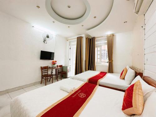 a hotel room with two beds and a table at Khách Sạn Ngọc Hà in Ho Chi Minh City