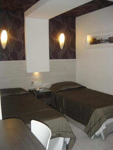 two beds in a room with a table and chairs at Bianca Praia Hotel in Recife