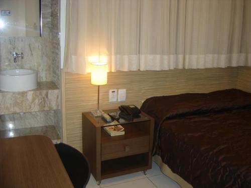 a hotel room with a bed and a table with a lamp at Bianca Praia Hotel in Recife
