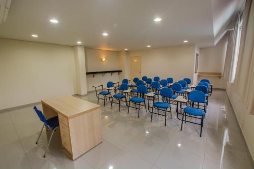 a conference room with blue chairs and a wooden podium at SJ Tour - San Juan Foz do Iguaçu in Foz do Iguaçu