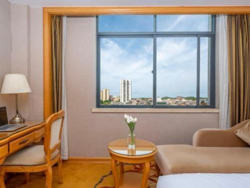 a living room with a table and a window at Vienna Hotel Guangxi Fangcheng in Fangcheng