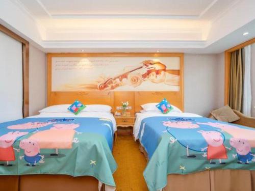 two beds in a room with a painting of pigs at Vienna Hotel Guangxi Fangcheng in Fangcheng