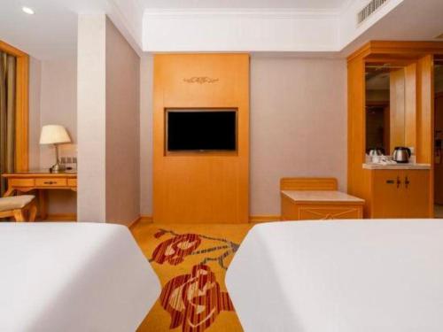 a hotel room with a bed and a television at Vienna Hotel Guangxi Fangcheng in Fangcheng