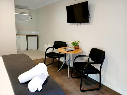 a living room with a table and chairs and a television at Higgins Lane Motel in Margaret River Town