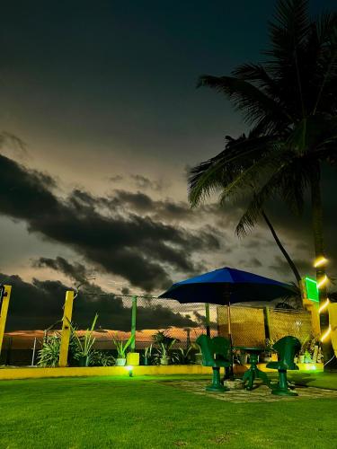 a table and chairs with an umbrella and a palm tree at The Family Beach Villa in Uswetakeiyawa
