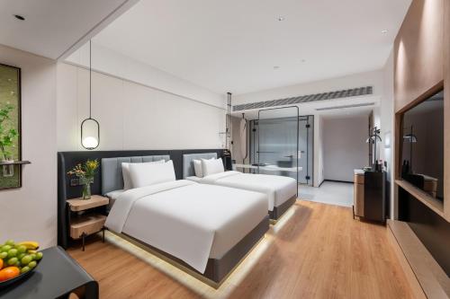 a bedroom with a large white bed and a television at KSpace KaiShi hotel in Guangzhou