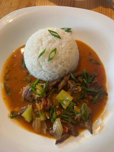 a white plate of food with rice and meat at Beymaral Lodge Jyrgalan in Dzhergalan