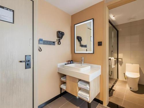 une salle de bain avec un lavabo et un miroir dans l'établissement GreenTree Inn Express Dongying Lijin County Ginza Market, à Dongying