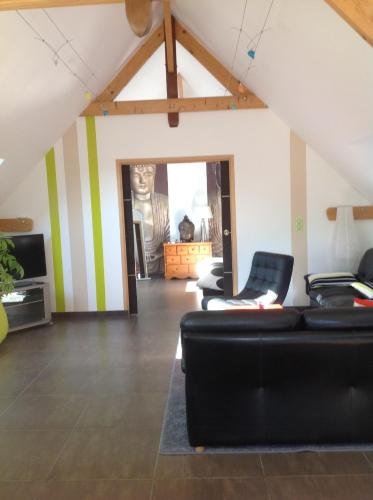 a living room with a black couch and striped walls at Le Sérènity in Le Landin