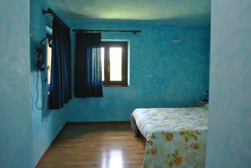 a blue room with a bed and a window at Agriturismo Oasi Belvedere in Monte San Pietrangeli