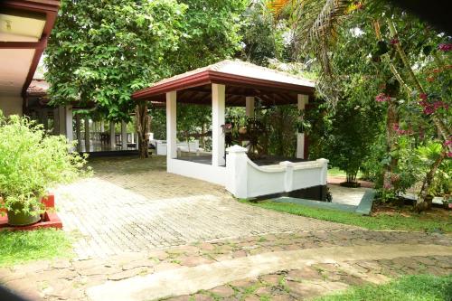 a gazebo in a yard next to a house at Mango Breeze Hikkaduwa in Gonapinuwala West