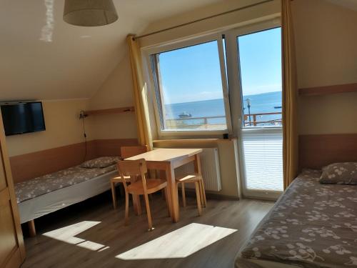 a room with a table and two beds and a window at Nad zatoką in Kuźnica