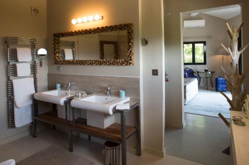 a bathroom with two sinks and a mirror at H&ocirc;tel La Maison de Crillon in Crillon-le-Brave
