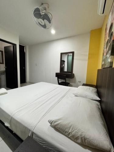 Una cama blanca grande en una habitación con espejo. en Hotel Gixael, en Santa Marta