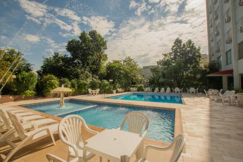 een zwembad met stoelen en een tafel en stoelen bij San Juan Tour in Foz do Iguaçu