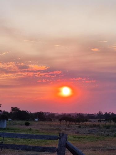 a sunset over a field with a fence at Cottonvale Country Lodge 