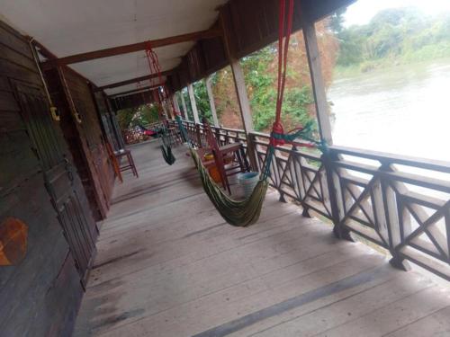 a porch with a hammock on the side of a building at Smiling Lao River View in Don Det