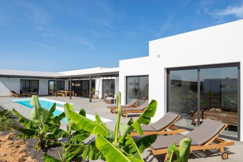 a house with a swimming pool and some chairs at Villa Alfa by FuerteventuraVillas in Lajares