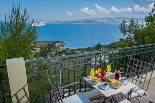 a table with food on a balcony with a view of the ocean at Ionian Vista Villas in Argostoli