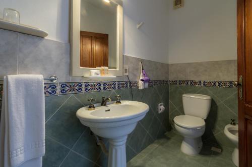 a bathroom with a sink and a toilet and a mirror at Don Antonio Posada in Colonia del Sacramento