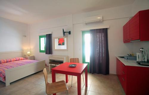 a living room with a red table and a kitchen at Kastellos Apartments Sikinos in Alopronia