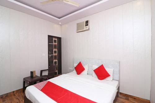 a bedroom with a bed with red pillows on it at OYO 81074 Hotel Adb in Faridabad