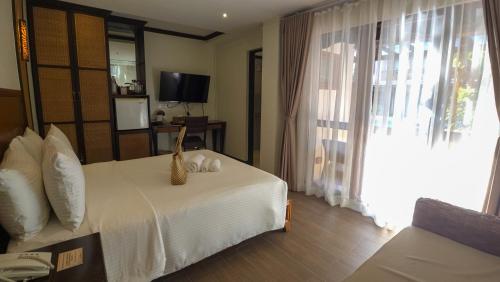 a bedroom with a bed and a tv and a window at Red Coconut Beach Hotel Boracay in Boracay