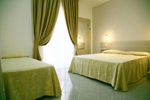 two beds in a hotel room with a window at Al Giglio - Affittacamere in Cariati